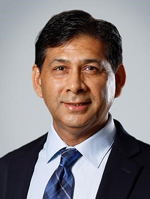 A professional portrait of Irfan Rahman, a middle aged man with short dark hair, tan skin and brown eyes. 